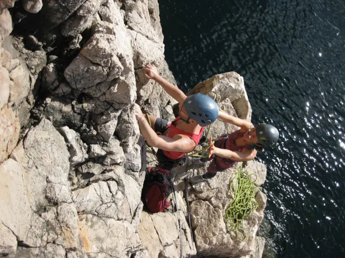 Climber being spotted at the start of a lead climb at Sagres