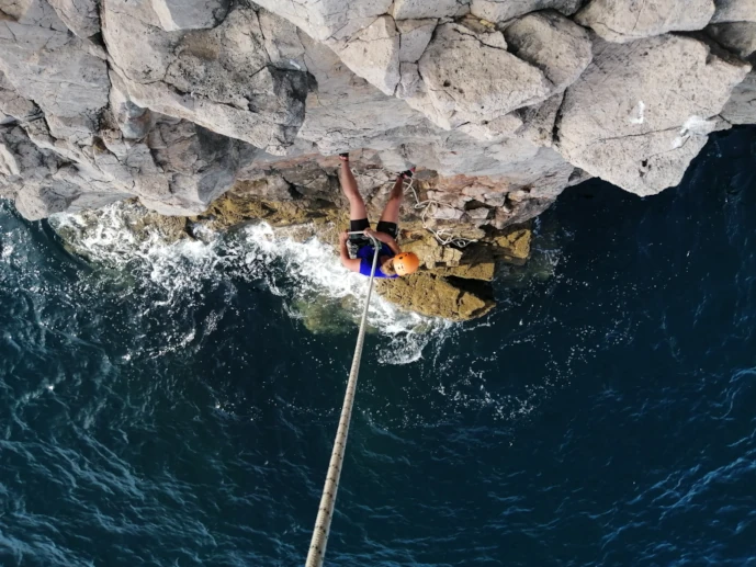 Climber rappeling down ocean cliff in Sagres