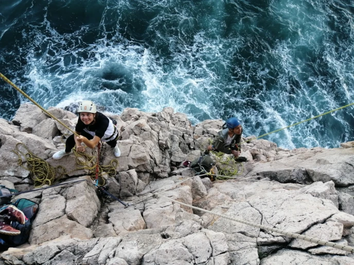 Belayers looking up while standing on a ledge in Sagres