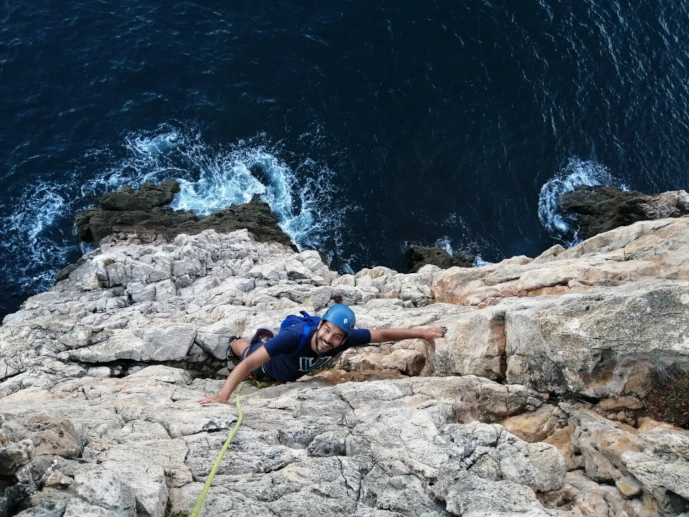 Climber taking a rest on a ledge in Sagres