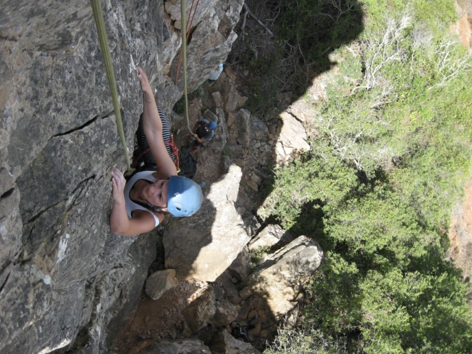 Climber halfway through a route at the Lagos climbins area as part of a top rope course